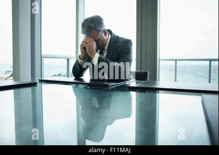 Caucasian businessman holding head in hands at conference table Stock Photo