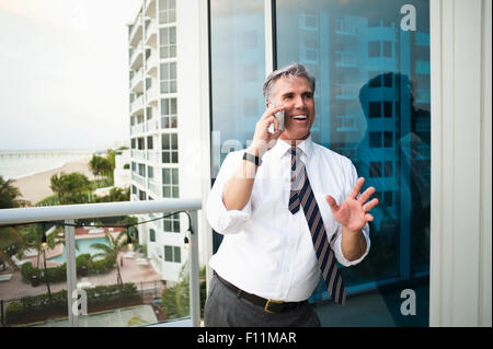 Caucasian businessman talking on cell phone on balcony Stock Photo