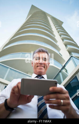 Low angle view of Caucasian businessman using cell phone at high rise building Stock Photo