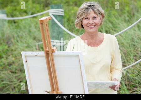 Older Caucasian woman painting outdoors Stock Photo