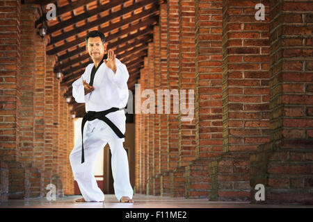 Hispanic man practicing martial arts in hallway Stock Photo