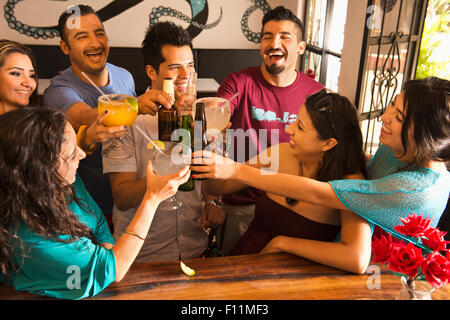 Hispanic friends toasting with drinks at bar Stock Photo