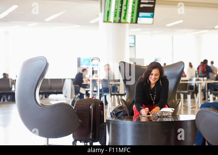 Hispanic businesswoman writing in airport waiting area Stock Photo