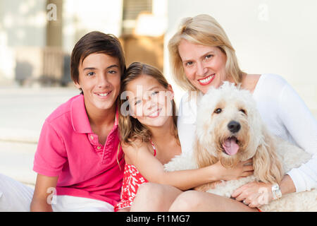 Smiling mother and children posing with dog outdoors