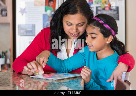Indian mother and daughter using digital tablet at counter Stock Photo
