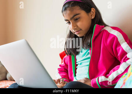 Indian girl using laptop on bed Stock Photo