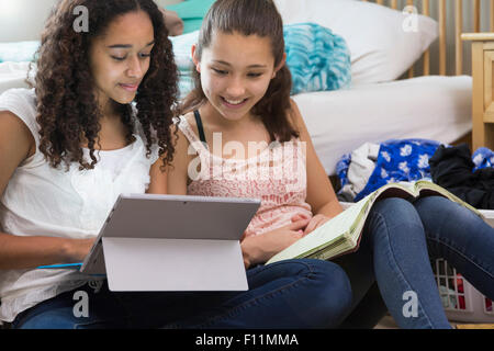 Teenage girls using digital tablet in bedroom Stock Photo