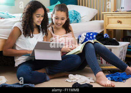 Teenage girls using digital tablet in bedroom Stock Photo