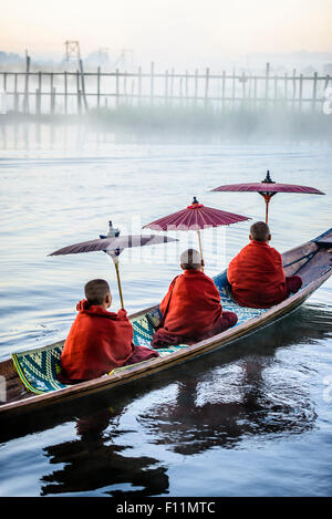 Asian monks under parasols in canoe on river Stock Photo