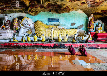 Asian monks praying to Buddha statue in temple Stock Photo