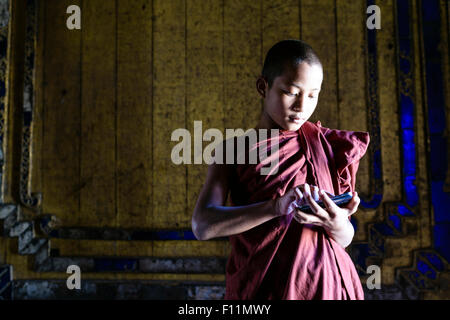 Asian monk-in-training using cell phone in temple Stock Photo