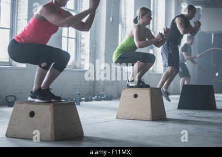 Athletes crouching on platforms in gym Stock Photo