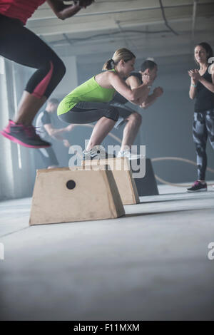Athletes jumping on platforms in gym Stock Photo