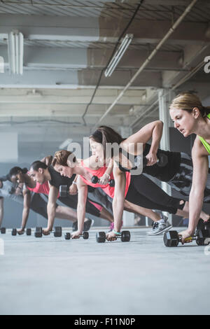 Athletes doing push-ups with dumbbells on floor Stock Photo