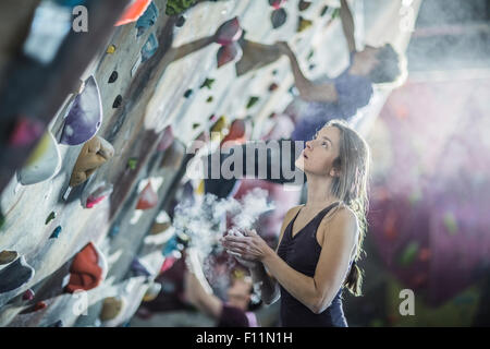Athlete chalking her hands at rock wall in gym Stock Photo