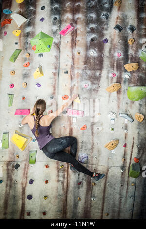 Athlete climbing rock wall in gym Stock Photo