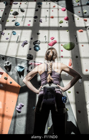 Athlete examining rock wall in gym Stock Photo
