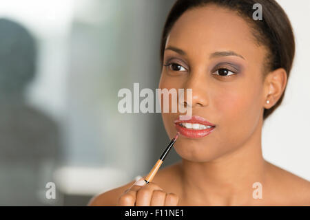 Mixed race woman applying lipstick Stock Photo