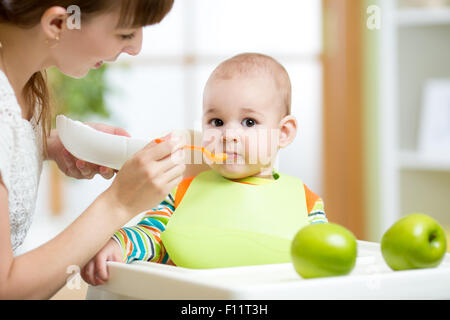 Happy mother spoon feeding her baby child Stock Photo
