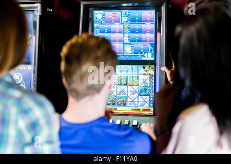 Young group of people gambling in a casino playing slot and various machines Stock Photo