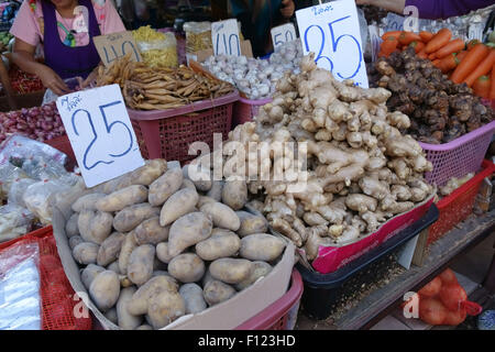 Root crops including potato, ginger, garlic, shallots, carrots and other produce on a stall in a Bangkok food market, Thailand Stock Photo