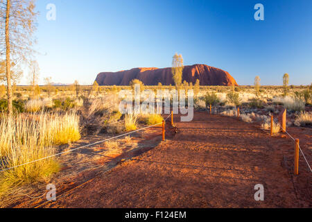 Majestic Uluru and the footpath to the viewing platform at sunrise on a clear winter's morning in the Northern Territory, Austra Stock Photo