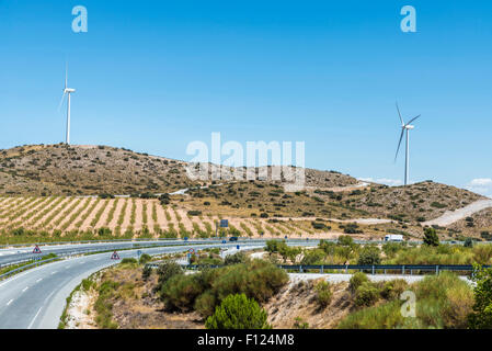 Highway through Andalusia between olive groves and a wind farm in Spain Stock Photo