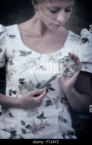 a woman is holding a big, old key in her hands Stock Photo