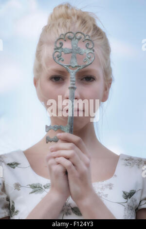 a woman is holding a big, old key in front of her face Stock Photo