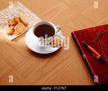 Morning breakfast coffee with vintage red notebook and biscuits Stock Photo