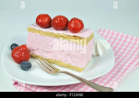 close up of a piece of strawberry fancy cake with whipped cream and pastry fork on  white plate, macro, detail, horizontal Stock Photo