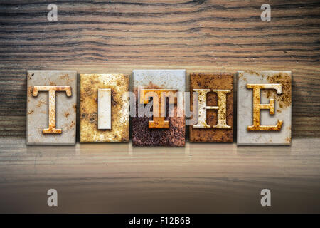 The word "TITHE" written in rusty metal letterpress type sitting on a wooden ledge background. Stock Photo