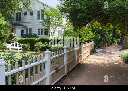 Picket fence, house, and unpaved sidewalk in the golfing village of Pinehurst, NC Stock Photo