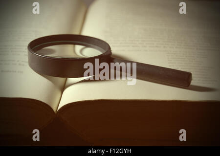 Magnifying glass on an open book with green background Stock Photo - Alamy