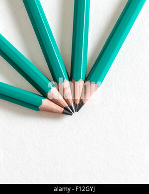 Upper view of black pencils on a piece of white paper. The texture of the paper is visible. Stock Photo