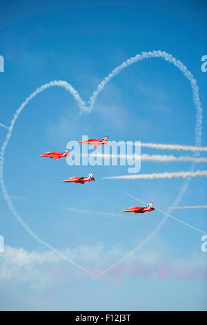 British Red Arrows from the Royal Air Force Jet fighter display team, flying through a jet trail heart at Southport Air Show Stock Photo