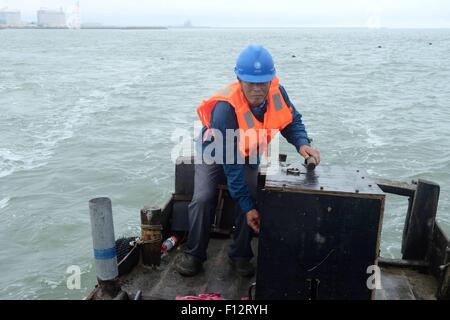 July 20, 2015 - Tsingtao, Shandong, CHN - Tsingtao, CHINA - July 20 2015: (EDITORIAL USE ONLY. CHINA OUT) Wu Deqing, the only electrician on Muguan Island. It is located in Boli Town of Tsingtao. The name is given by the story that First Emperor of Qin went to Langya Pavilion to ask for immortality, and his officers took a bath on the island. There are 56 families and 50 families live on aquiculture. Wu retired from army and went back to his hometown Muguan Island in 1976, and there is no electricity at all. Fishermen bought an electric generator and asked him to be in charge of generating ele Stock Photo
