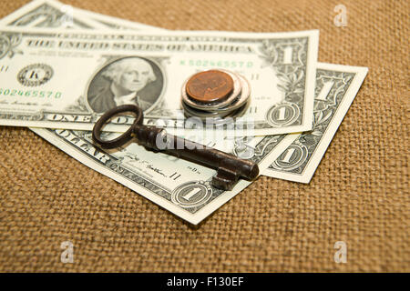 Dollars banknotes, coins and key on an old cloth Stock Photo