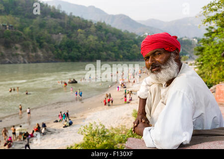 Portrait of a man, watching pilgrims, who are taking bath at the banks of the holy river Ganges, Rishikesh, Uttarakhand, India Stock Photo