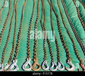 Rusty tow chains offered for sale at a carboot sale, laid out in vertical lines on a green groundsheet Stock Photo