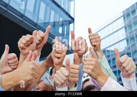 Group of business people holding their thumbs up next to the office outdoors Stock Photo