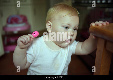 An eleven month old baby chewing on a plastic rattle to alleviate the pain and discomfort of tooth ache. Stock Photo