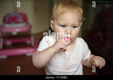 An eleven month old baby chewing on a small plastic rattle to alleviate the pain and discomfort of tooth ache. Stock Photo