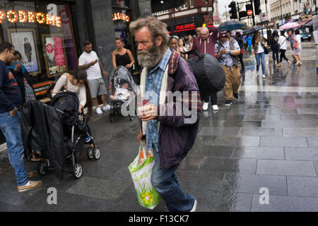 London, UK. Sunday 23rd August 2015. Heavy summer rain showers in the West End. People brave the wet weather armed with umbrellas and waterproof clothing. Stock Photo