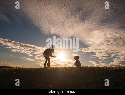 Silhouette of a girl with a baby learning to walk Stock Photo