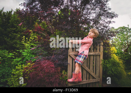 Portrait of a boy standing on wooden gate, looking up Stock Photo