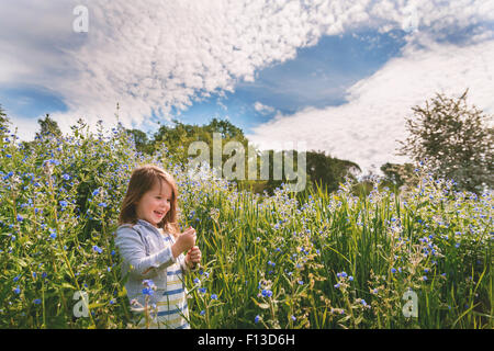 Smiling Girl picking flowers in field Stock Photo