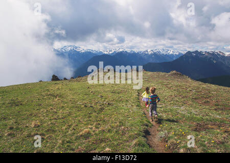 Boy and girl running along a mountain path Stock Photo