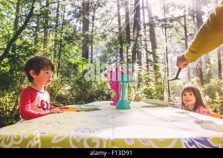 Two children sitting at picnic table in forest Stock Photo