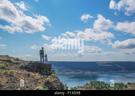 Rear view of father and daughter standing on top of a mountain Stock Photo
